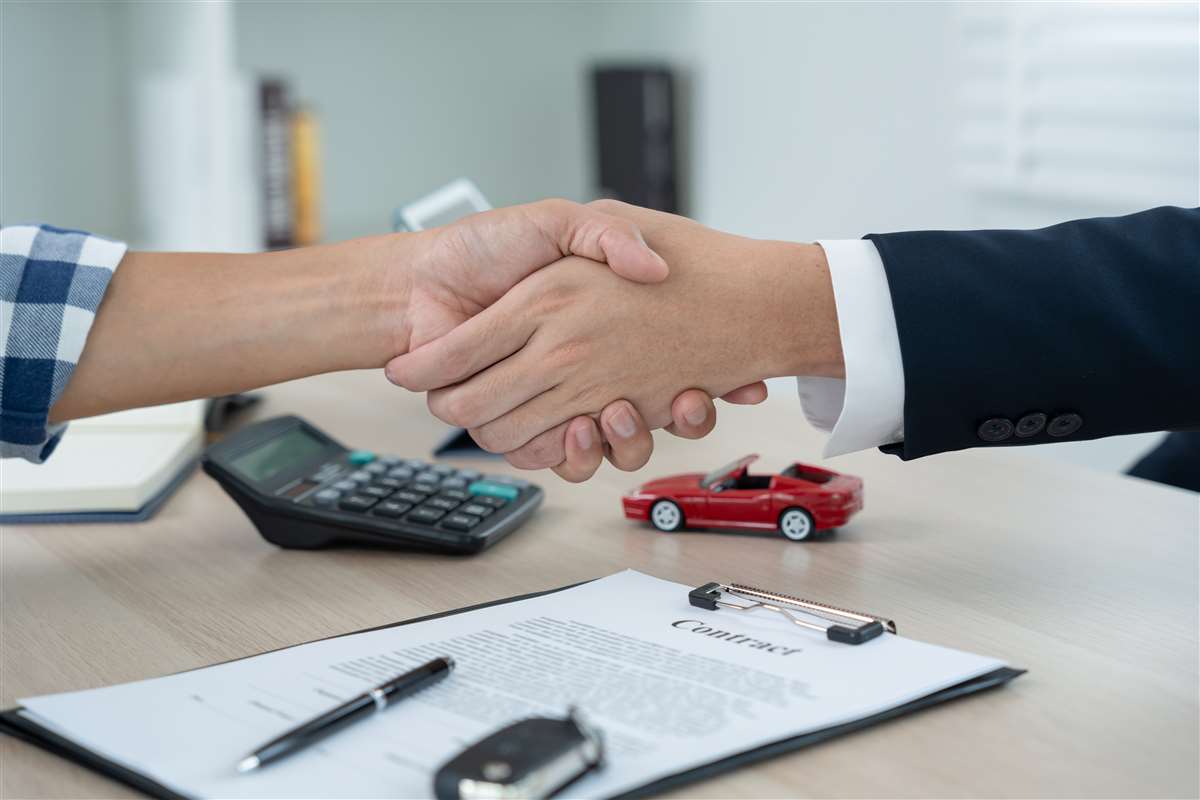 due mani si stringono dopo la firma di un contratto auto