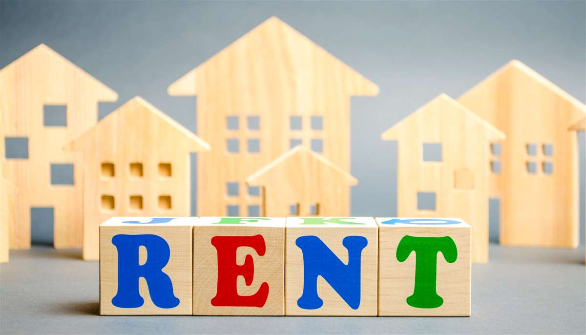 scritta rent in primo piano, sullo sfondo modellini di case in legno