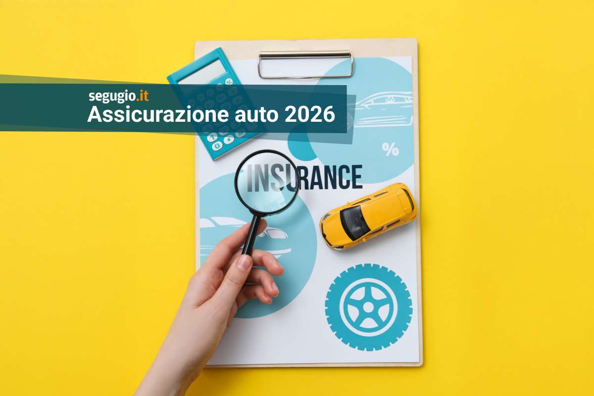 lente di ingrandimento su contratto di assicurazione, vicino a modellino di auto e calcolatrice
