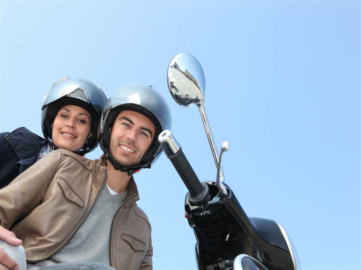 coppia di giovani che indossano il casco in sella a uno scooter