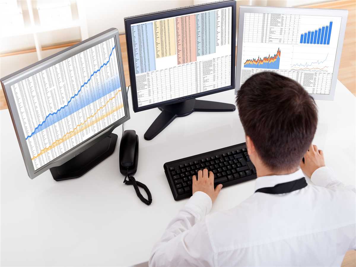 operatore finanziario davanti a schermi con grafici e numeri