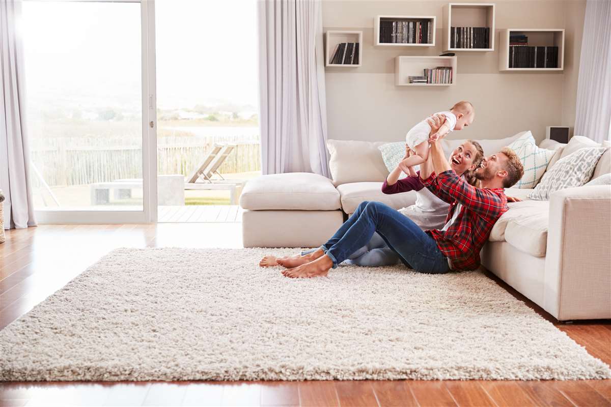 coppia felice gioca con figlio sul tappeto di casa