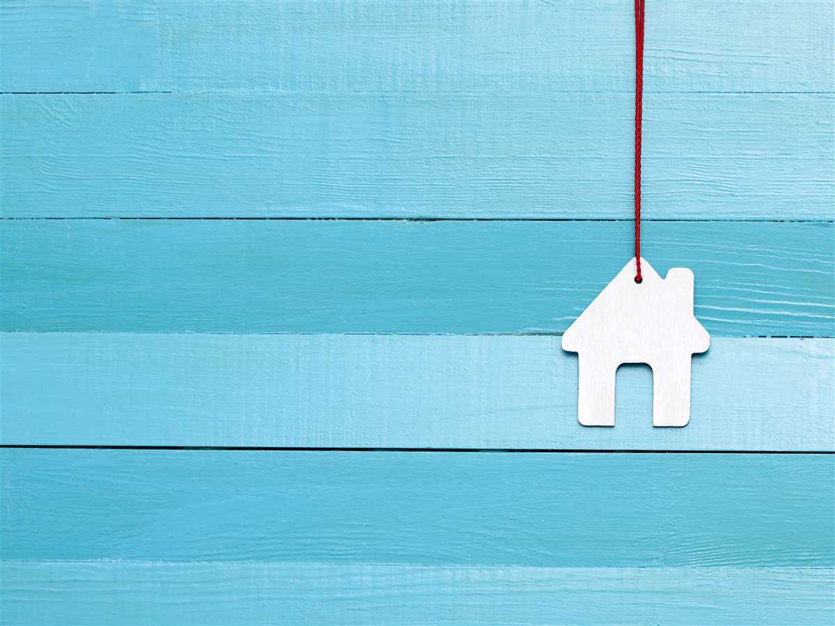 modellino di casa legato a un laccio rosso su sfondo azzurro