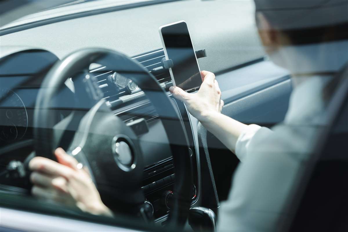 una donna alla guida di un auto prende il cellulare