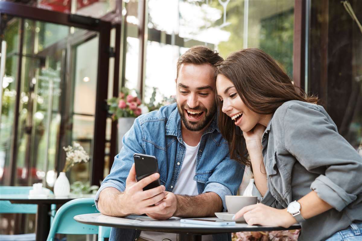 giovane coppia innamorata usa cellulare al tavolino di un bar