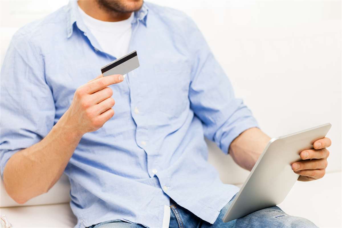 giovane seduto su un divano effettua pagamento online con carta