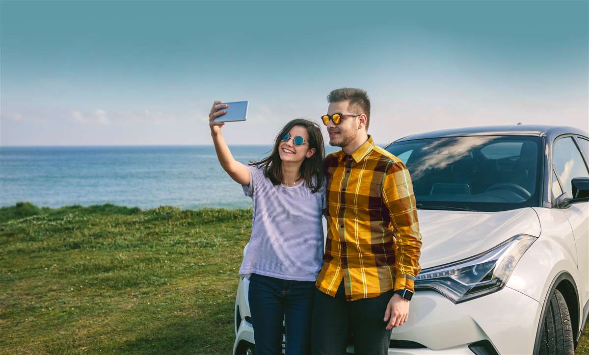 coppia felice si scatta selfie con auto come sfondo