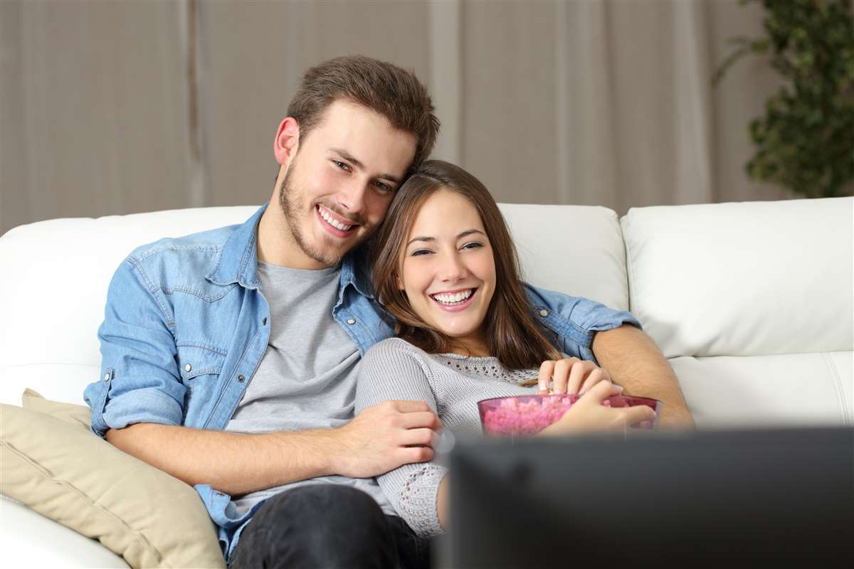 giovane coppia felice guarda film sul divano