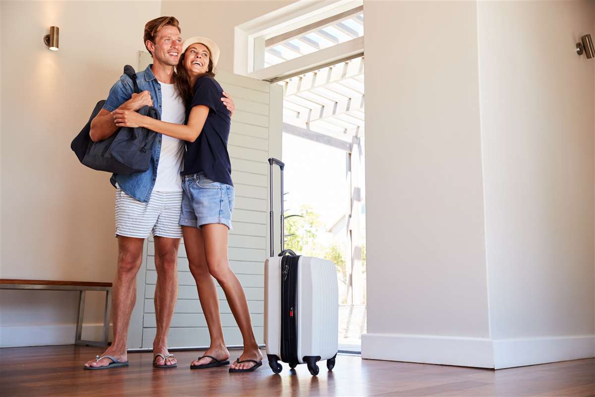 coppia di giovani felice in appartamento di vacanze con la valigia