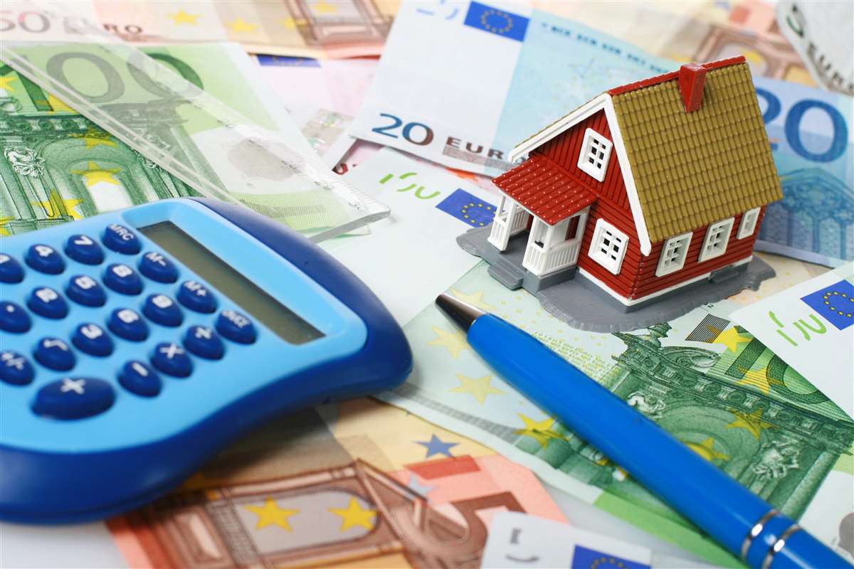 modellino di casa, calcolatrice, penna su banconote sparse