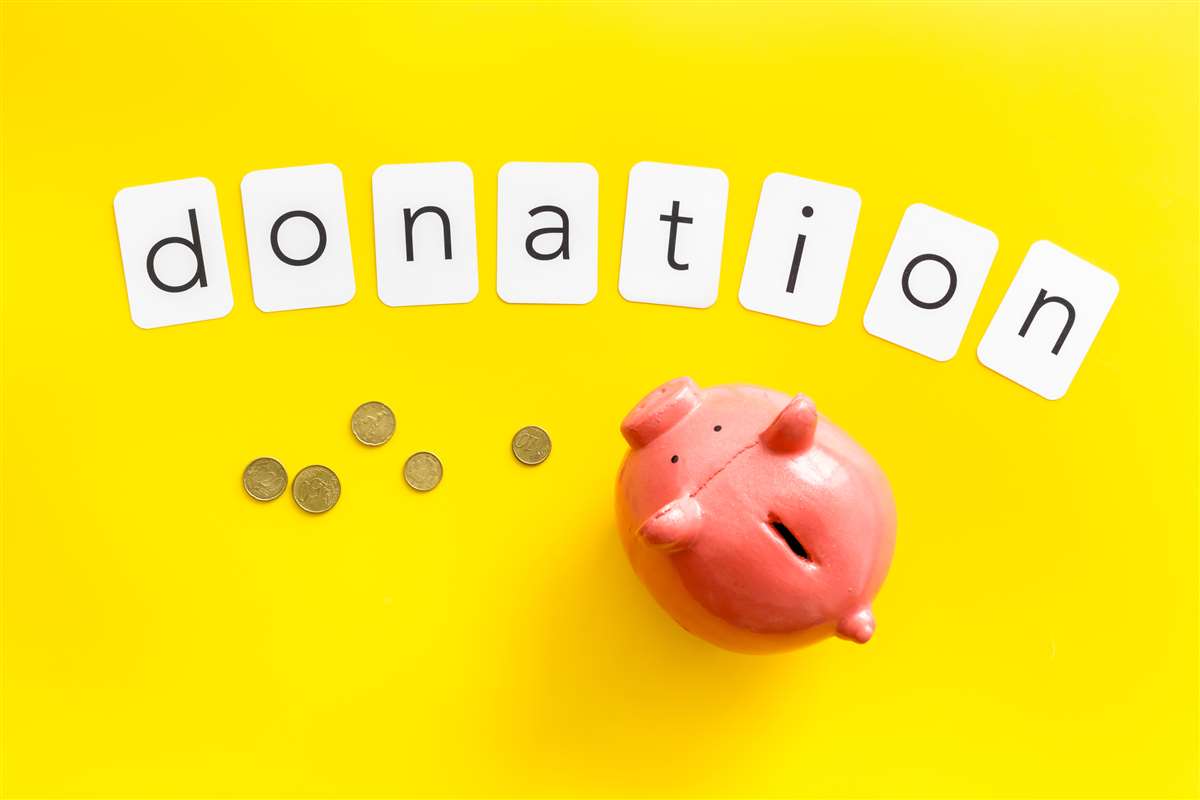 donazione in denaro scritta donation sopra ad un salvadanaio e a monete sparse