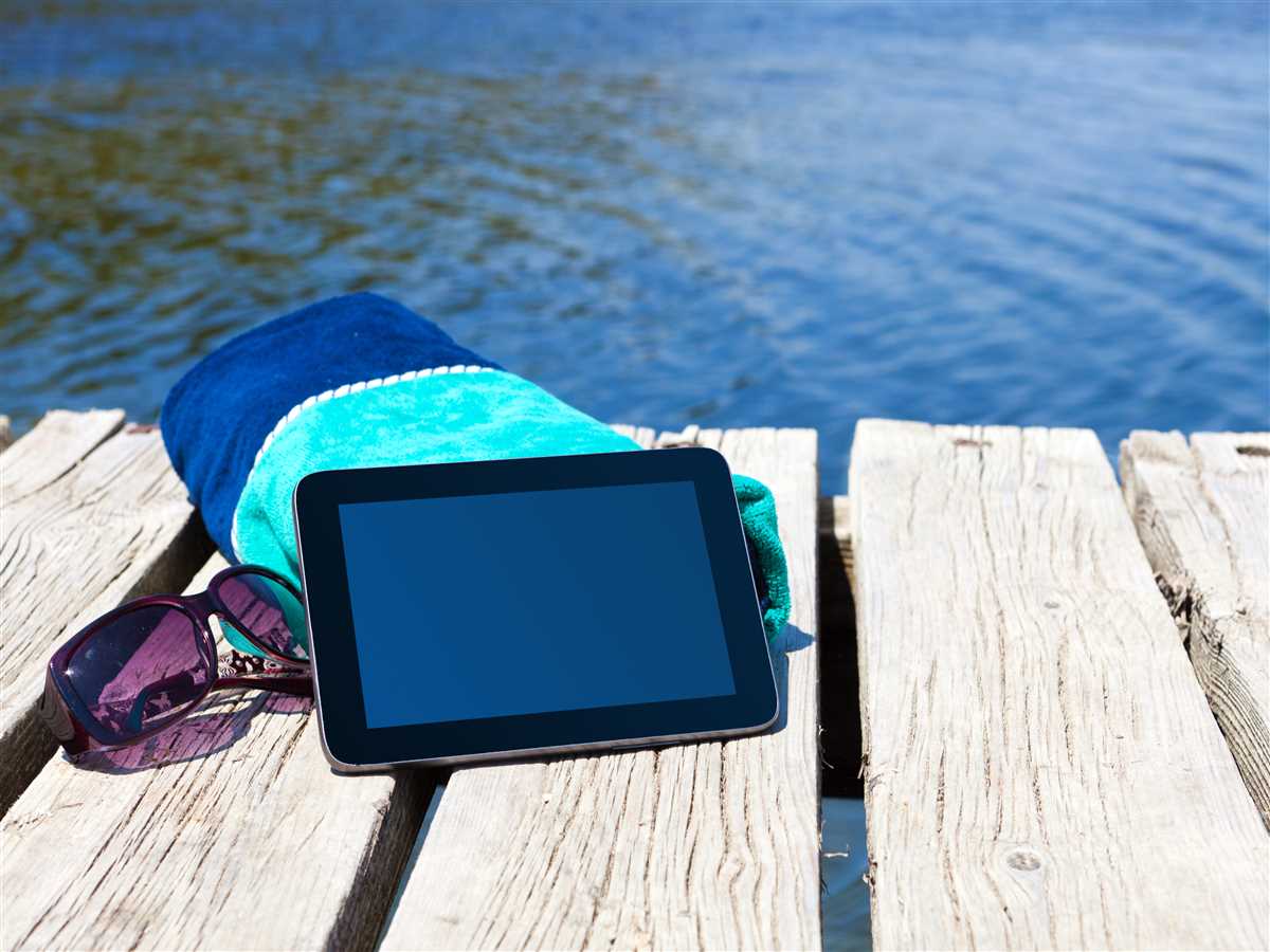 tablet poggiato su un asciugamano su un molo vista mare