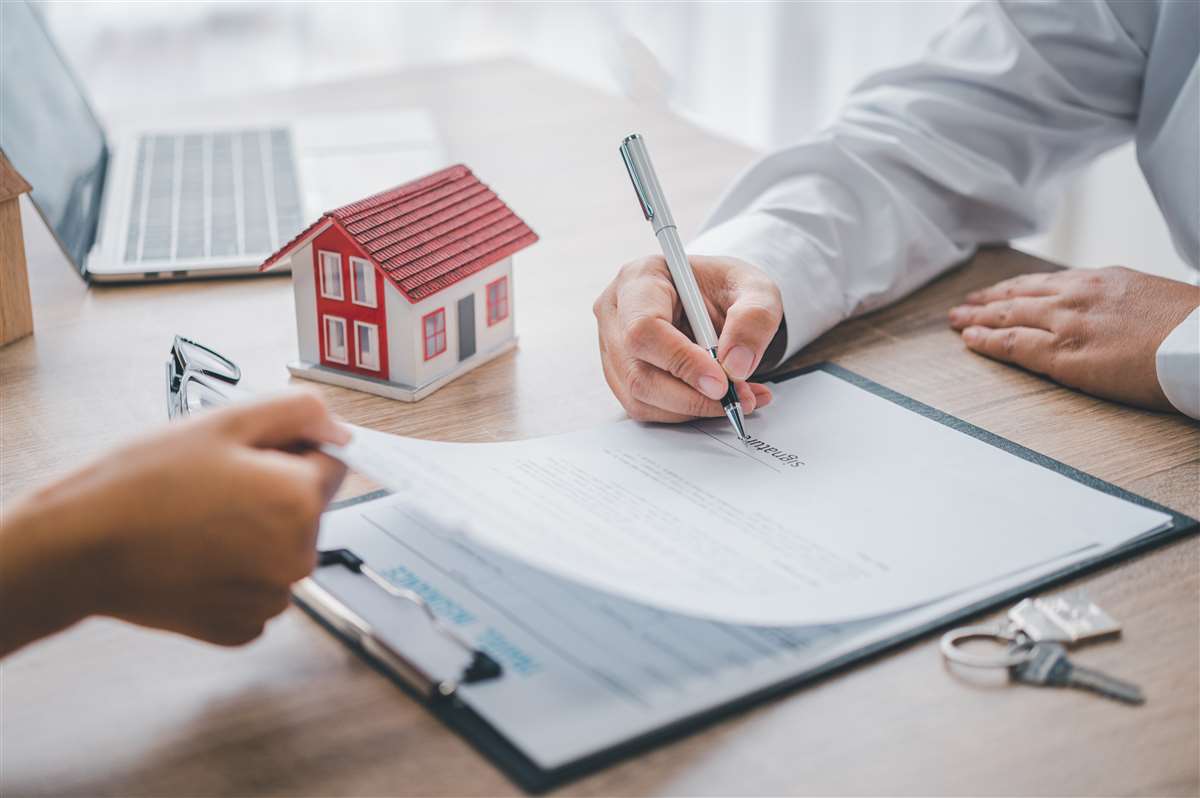 pre-delibera mutuo un cliente firma la pre-delibera del mutuo vicino a un modellino di casa