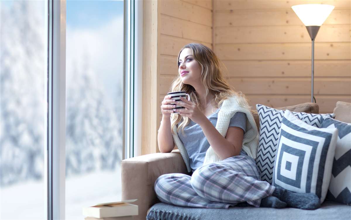 giovane donna beve tazza di caffÃ¨ sul divano di casa