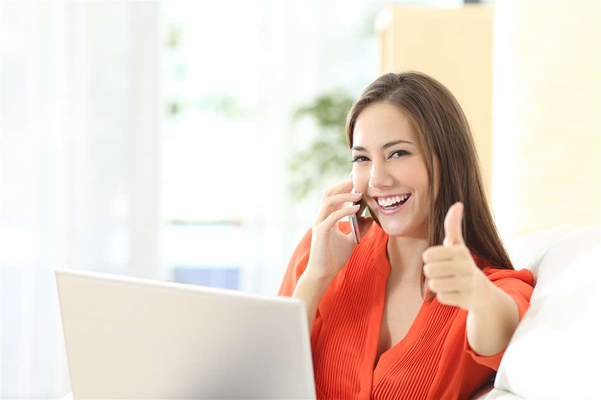 donna al computer che parla al telefono e fa il segno ok con la mano