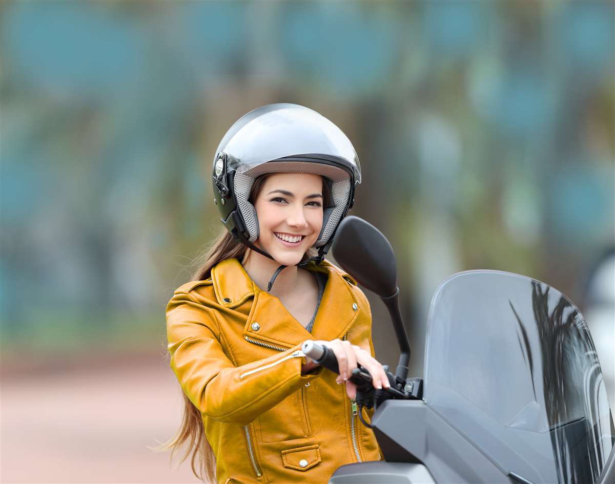 motociclista con casco in sella a uno scooter