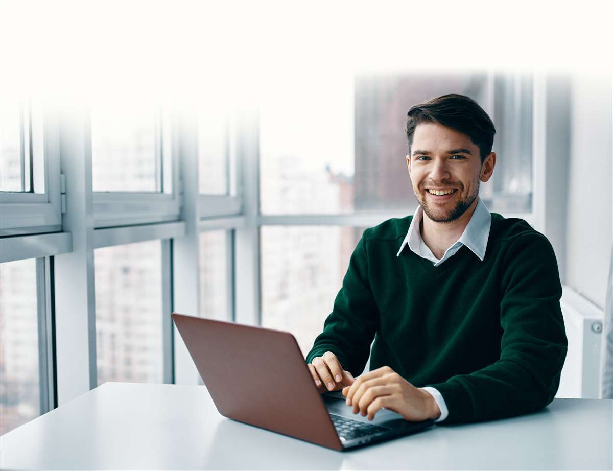 giovane uomo sorridente a lavoro con il suo laptop