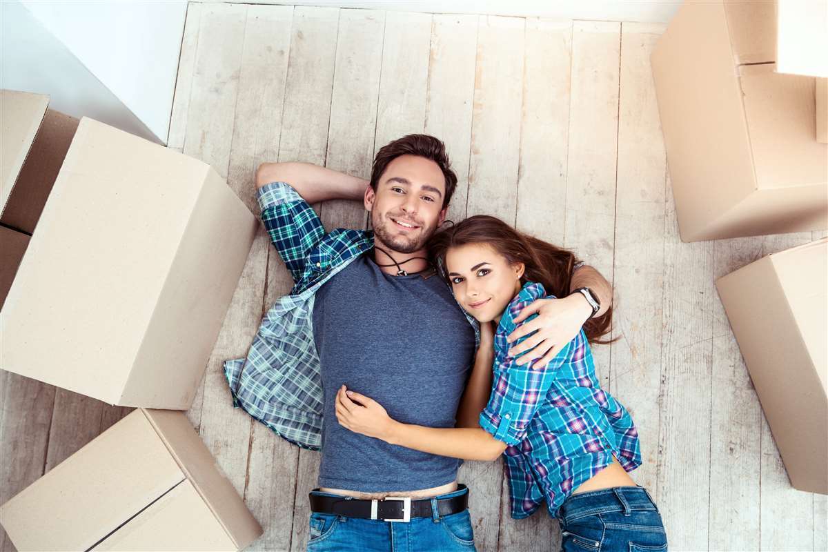 giovane coppia sul pavimento di casa nuova con scatoloni da trasloco