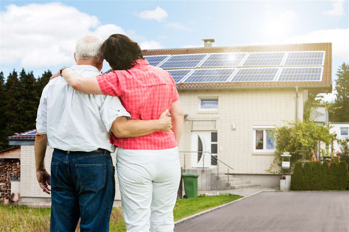 coppia anziana osserva pannelli solari installati sul tetto di casa