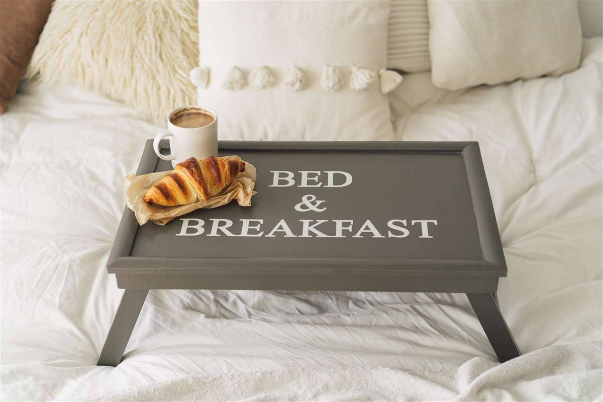 letto con vassoio poggiato con colazione e scritta bed and breakfast