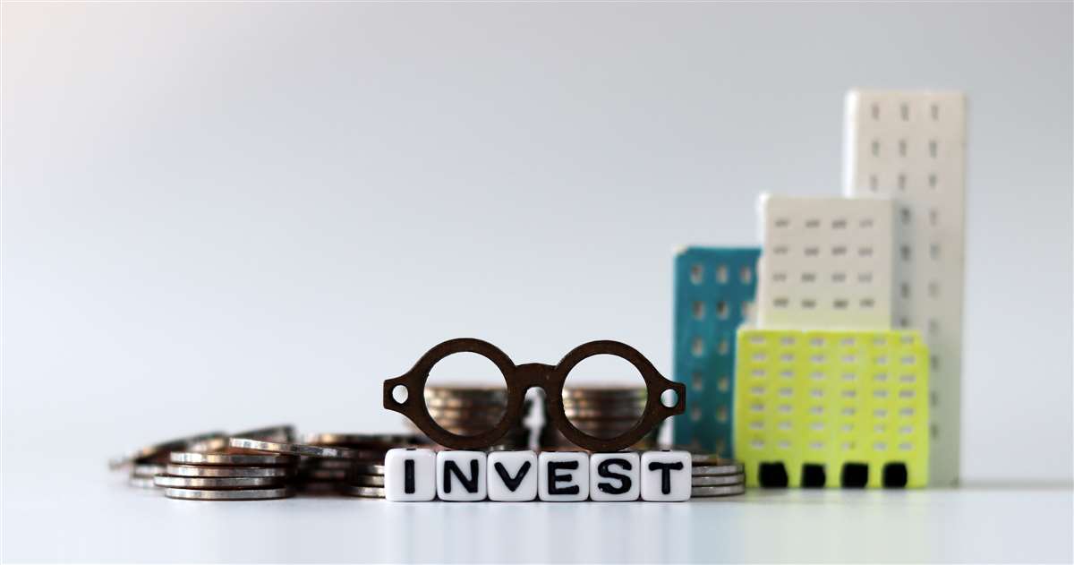 occhiali in miniatura sul cubo bianco recante la parola invest