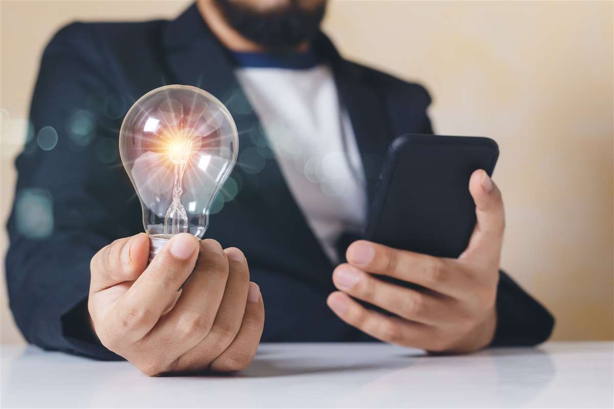tim energia uomo tiene in una mano una lampadina e nell'altra un cellulare