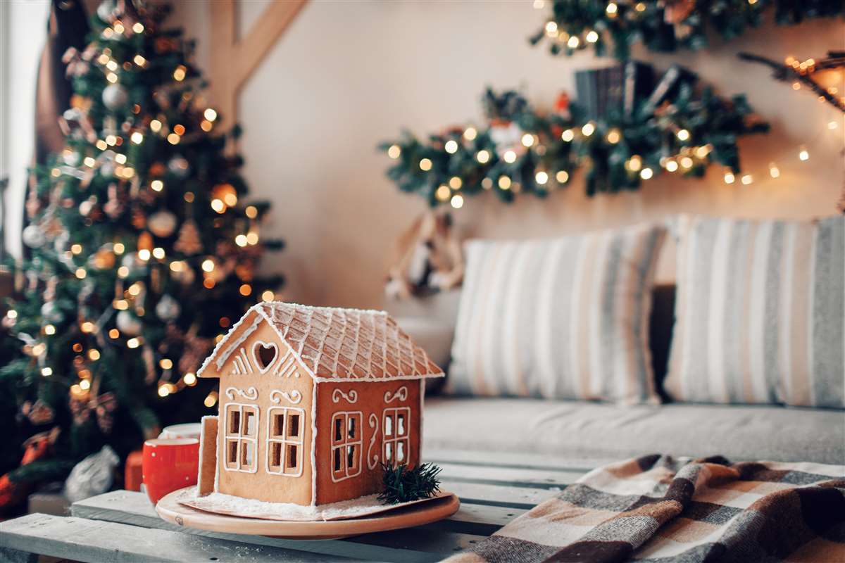 casa di marzapane su tavolino con albero di natale e decorazioni come sfondo