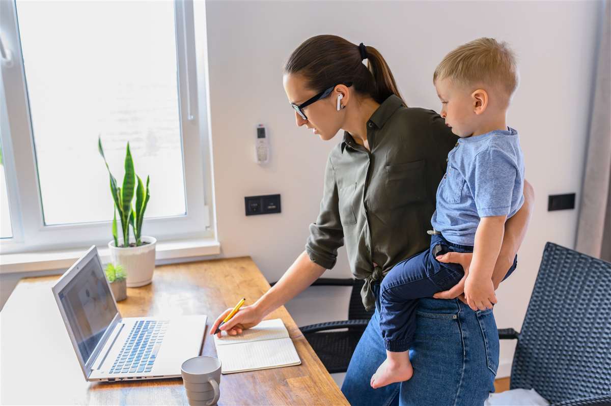 madre che lavora al pc con figlio in braccio