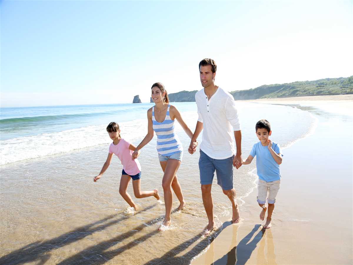 famiglia si tiene per mano camminando sulla spiaggia