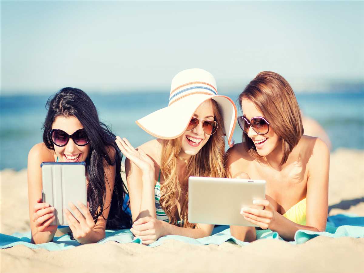 tre amiche prendono il sole in spiaggia mentre guardano serie tv sul tablet