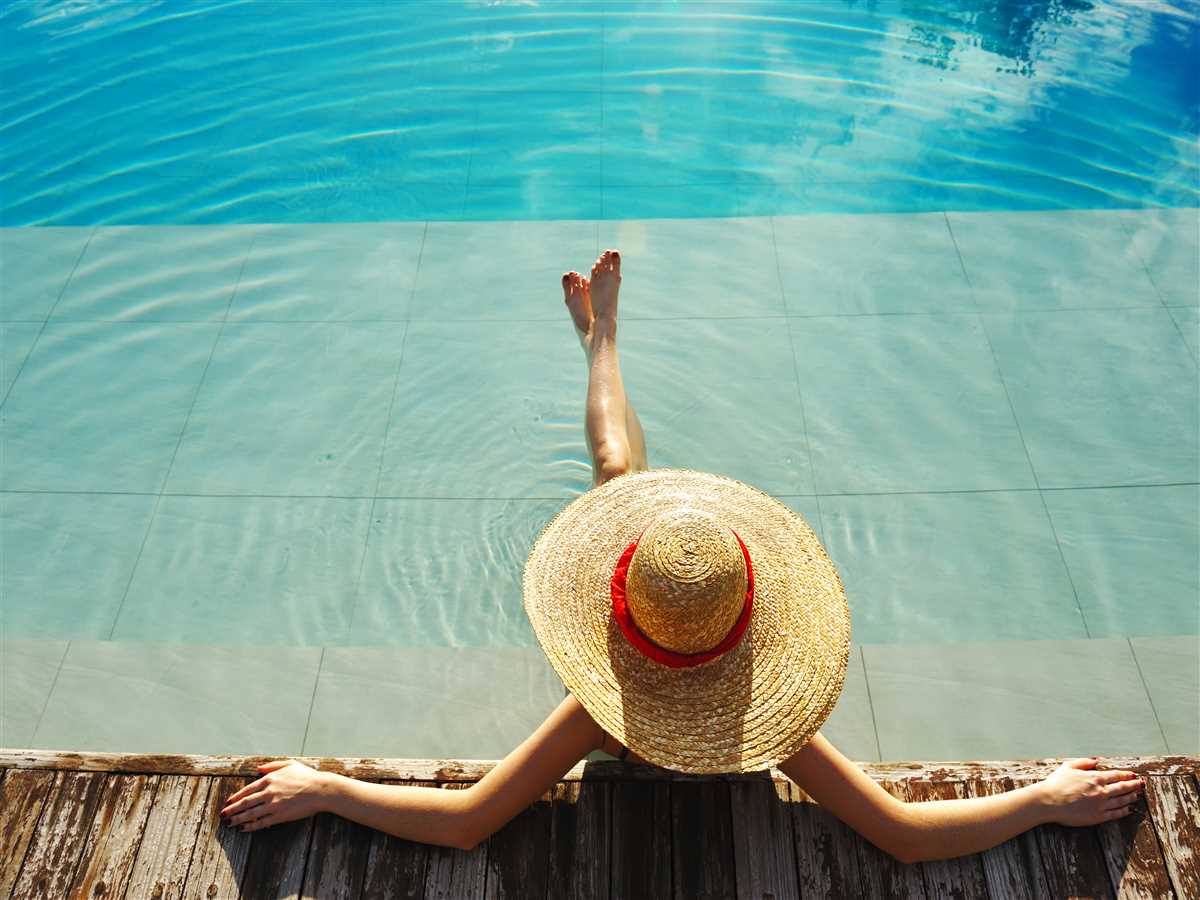donna con paglia si rilassa in piscina con le gambe incrociate