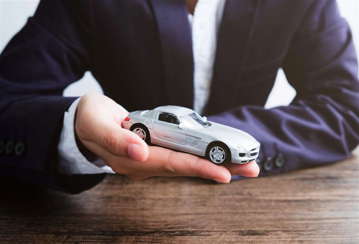 massimale risarcimento assicurazione un agente assicurativo tiene in mano un modellino di auto