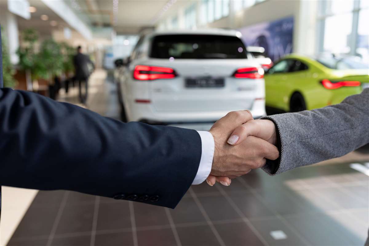 mercato auto nuove un agente di vendita e una cliente si stringono la mano per l'acquisto di un'auto
