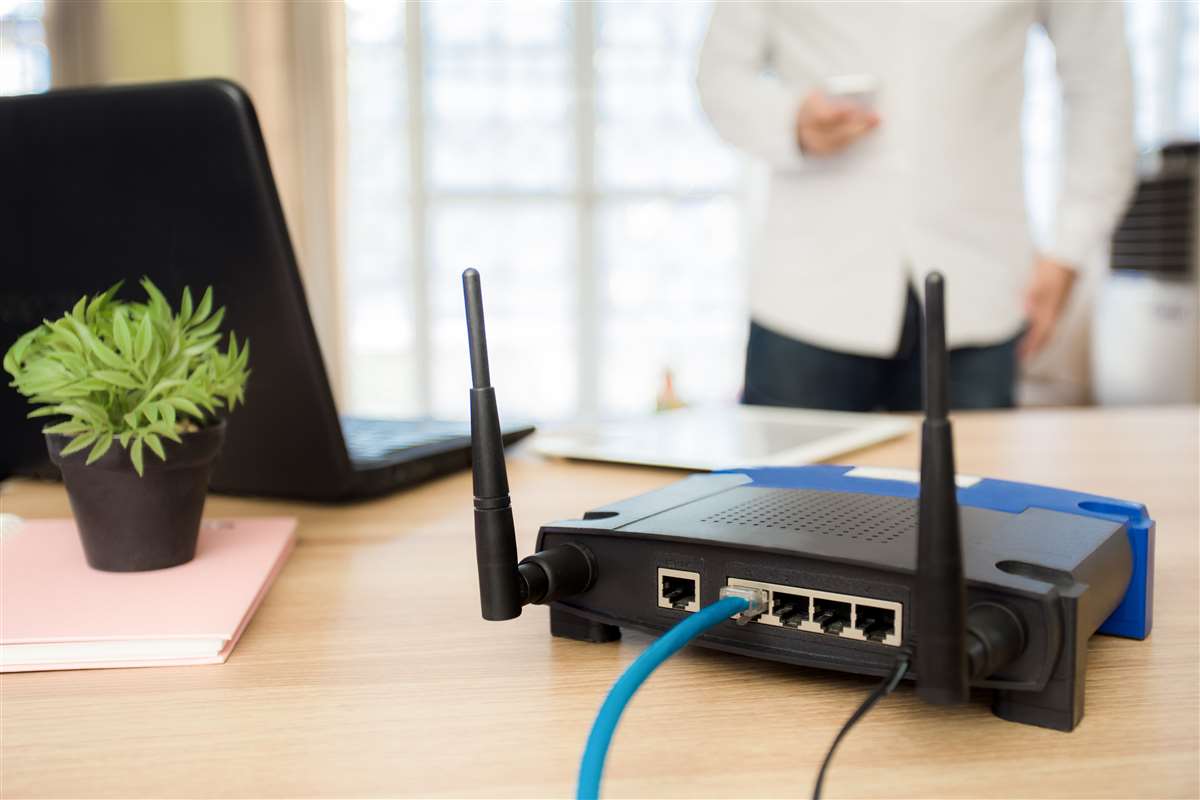 scrivania con modem e computer, sullo sfondo un ragazzo