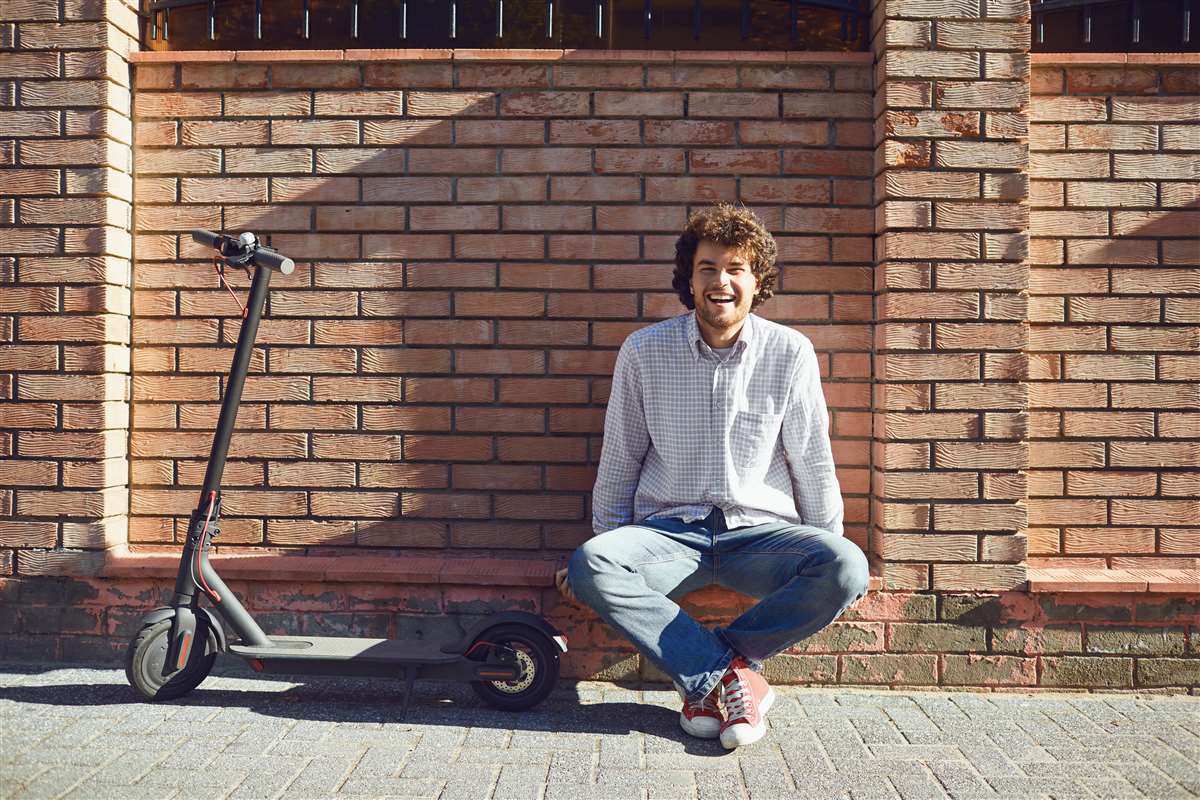 giovane guida uno scooter elettrico su una strada cittadina