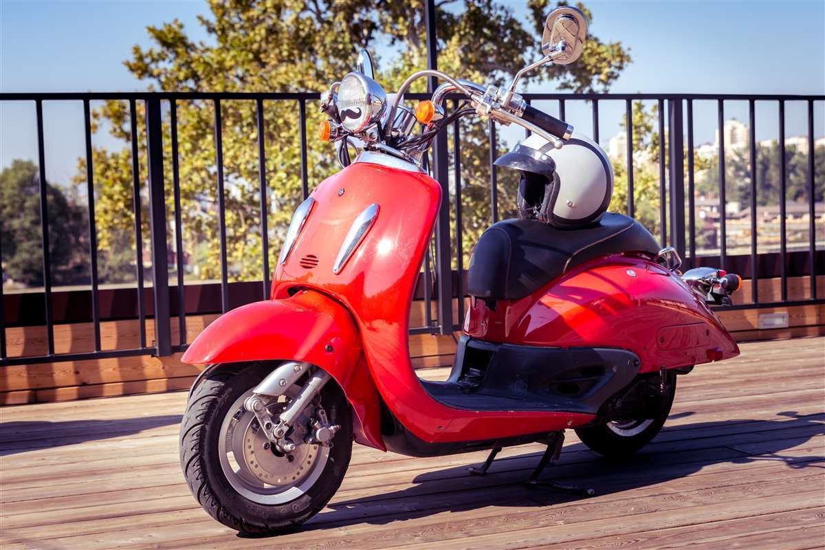 scooter di colore rosso con un casco sulla sella