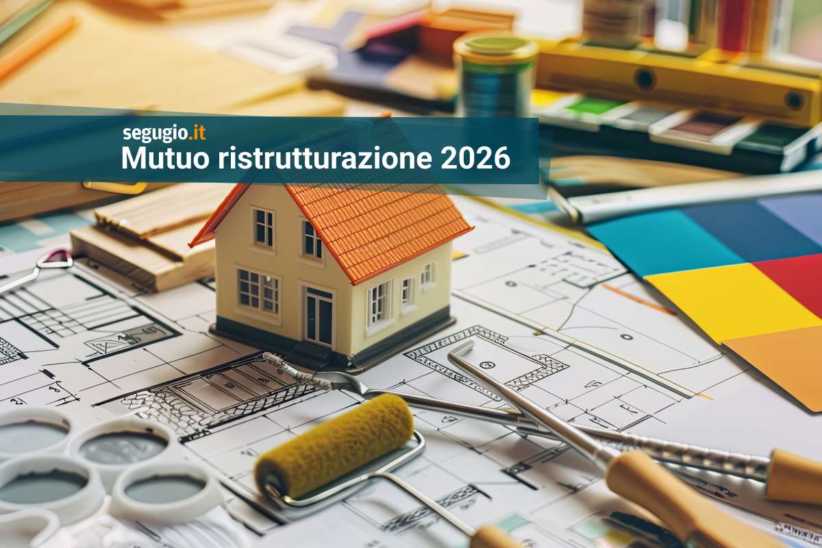 modellino di casa sopra a planimetrie e vicino ad attrezzi di ristrutturazione