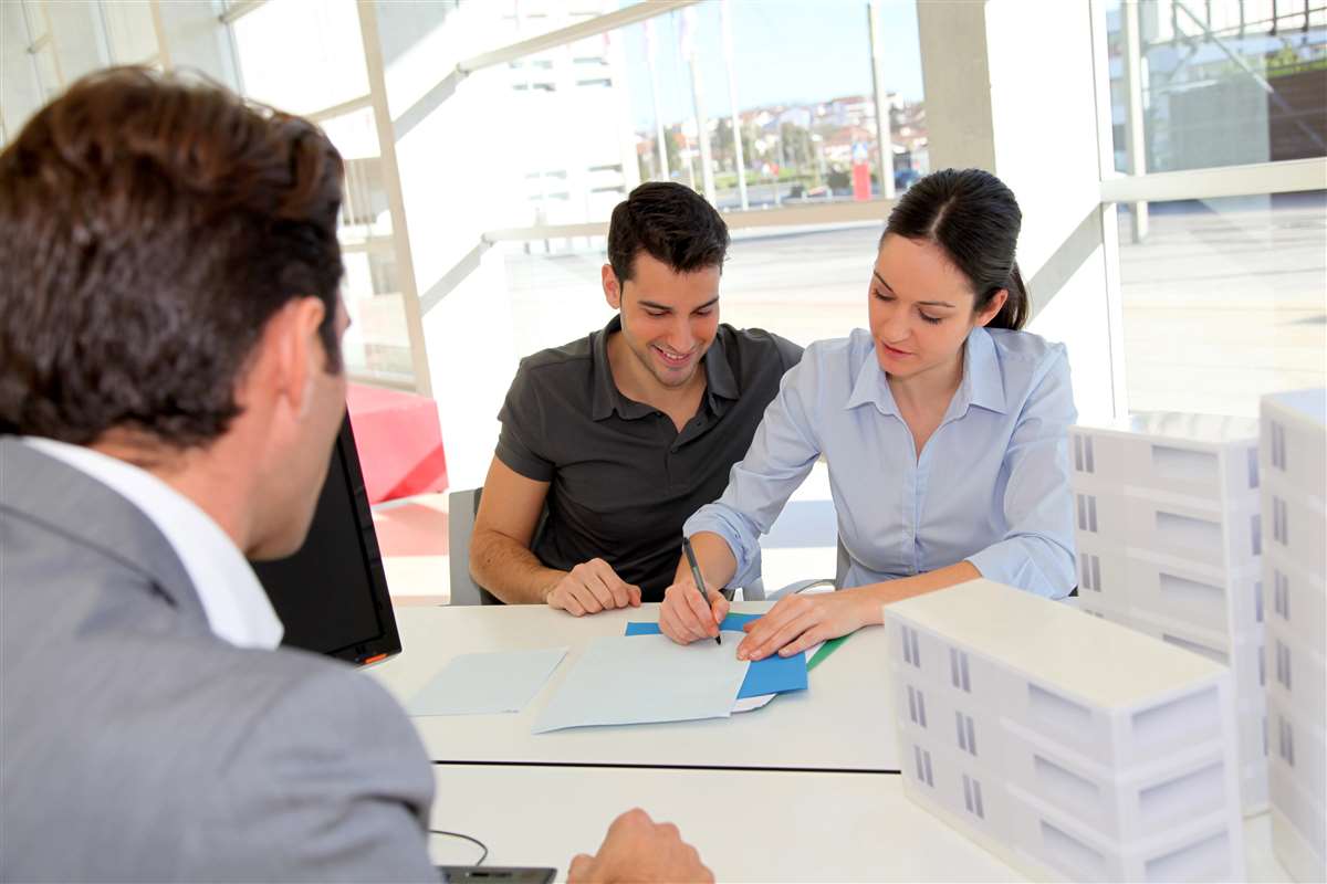 consulente di mutui propone un contratto di mutuo ad acquirenti, vicino a modellini di case