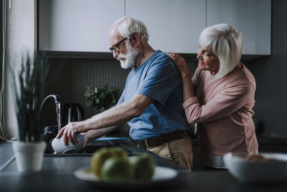 coppia pensionati lava piatti in cucina