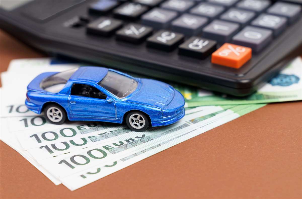 modellino di auto sopra a banconote da 100 euro e vicino a calcolatrice
