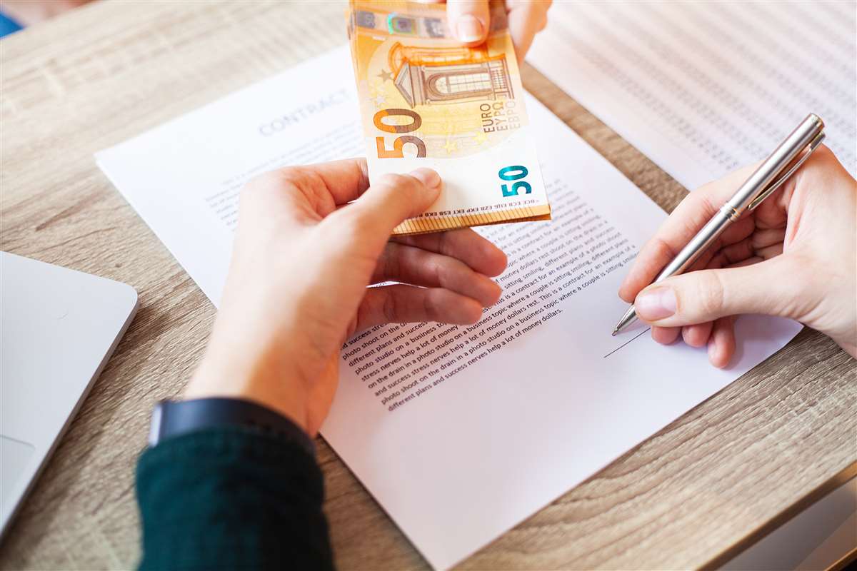 una persona che firma un contratto e riceve banconote