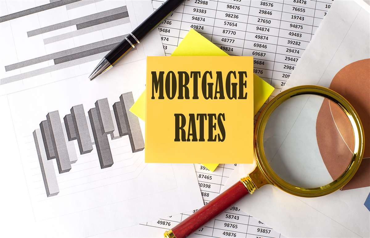scritta mortgage rates su post it, vicino a lente di ingrandimento e grafici economici