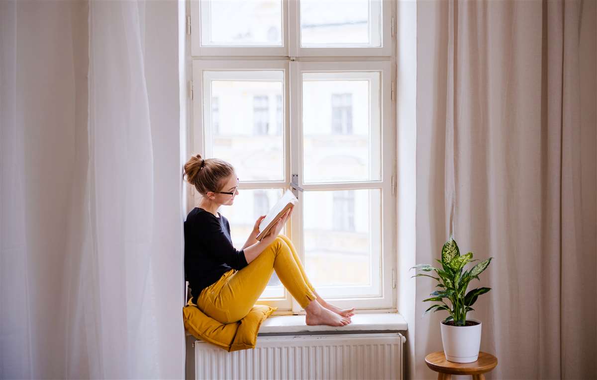 giovane studentessa legge libro sul davanzale della finestra