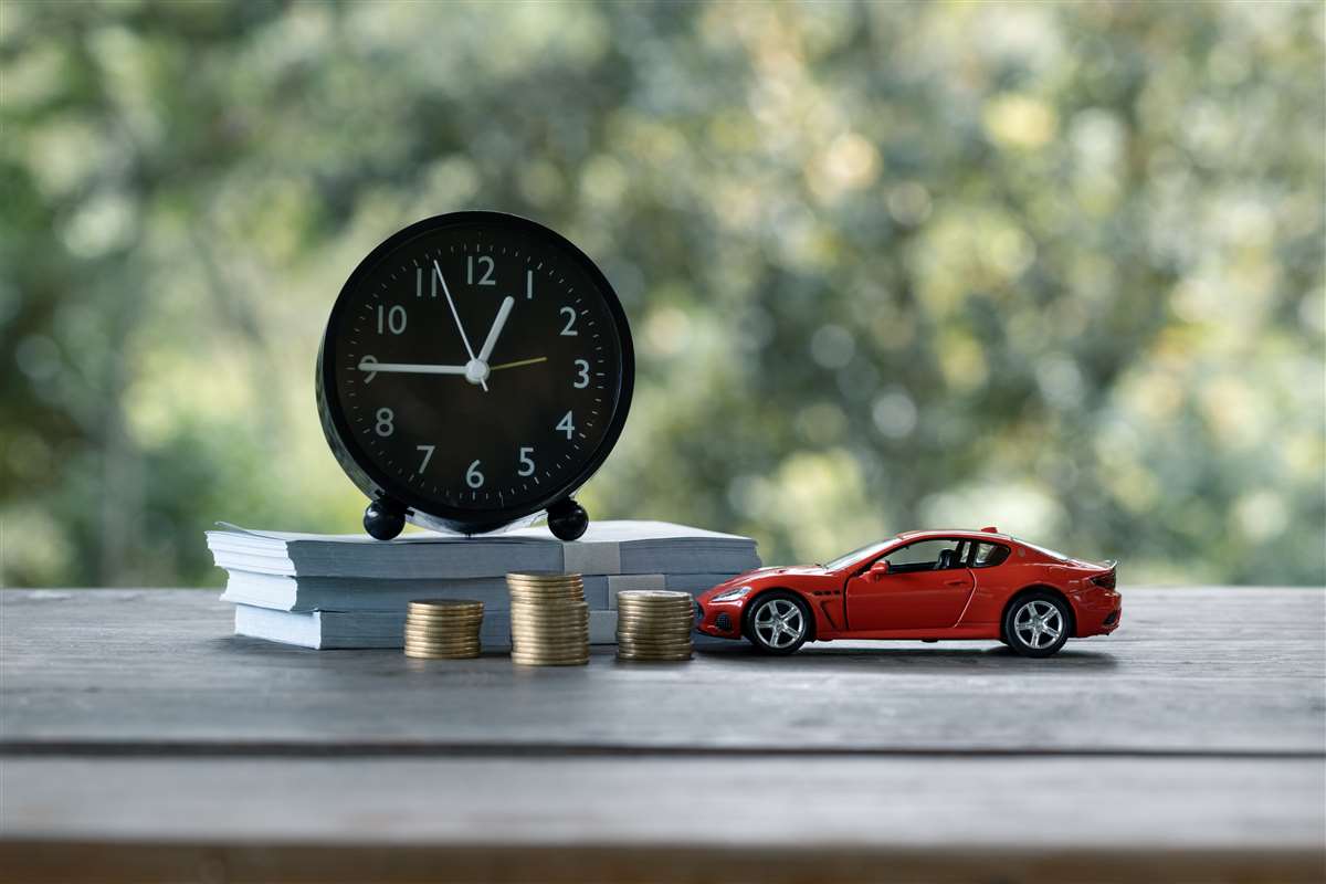 modellino di auto, pile di monete, banconote e sveglia