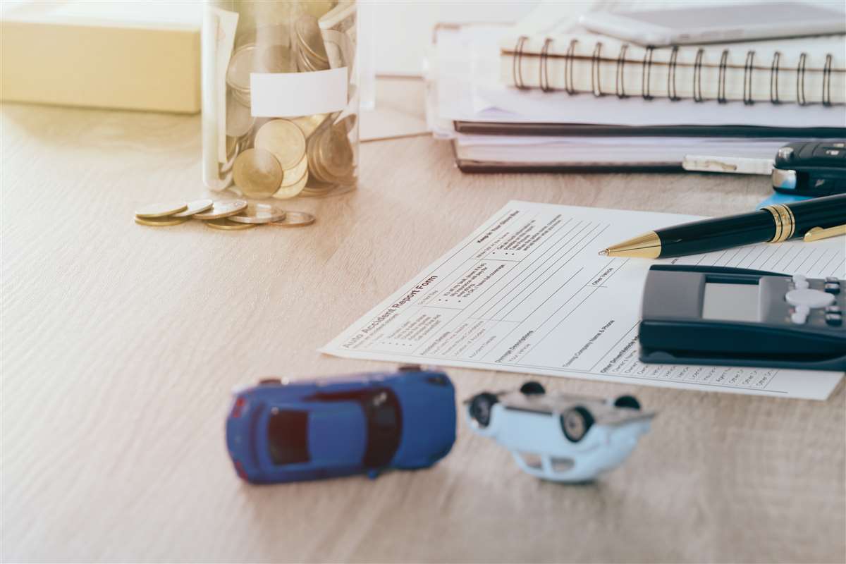 contestazione assicurazione auto modulo reclamo assicurazione con modellini auto su scrivania e monete