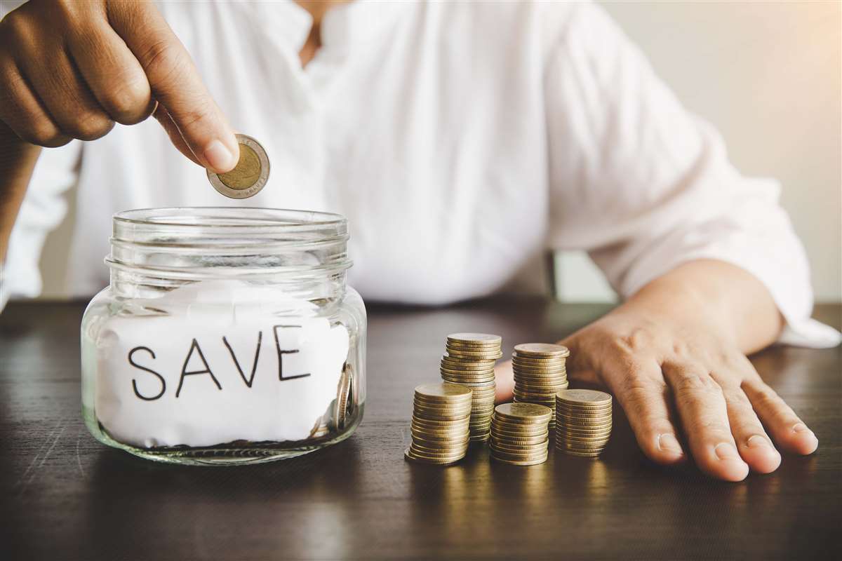 un uomo mette una moneta in un barattolo per risparmiare