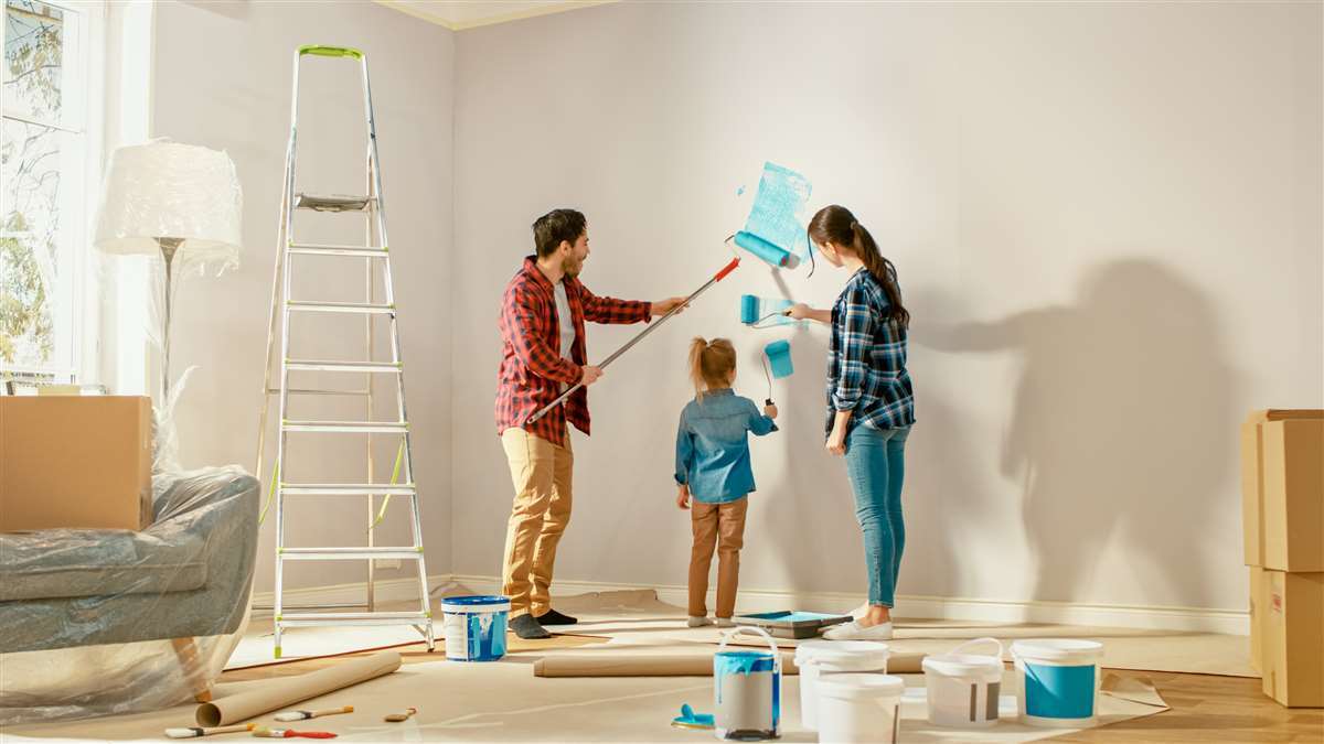 coppia giovane mostra come dipingere i muri alla figlia