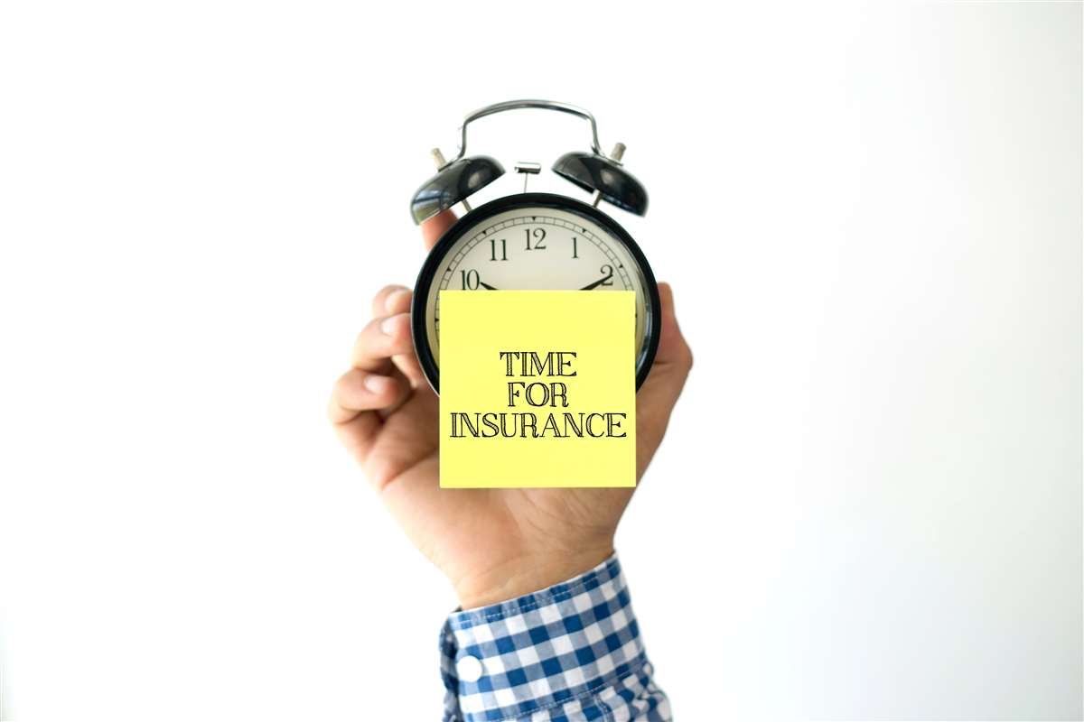 mano tiene una sveglia con un post it che mostra la scritta time for insurance