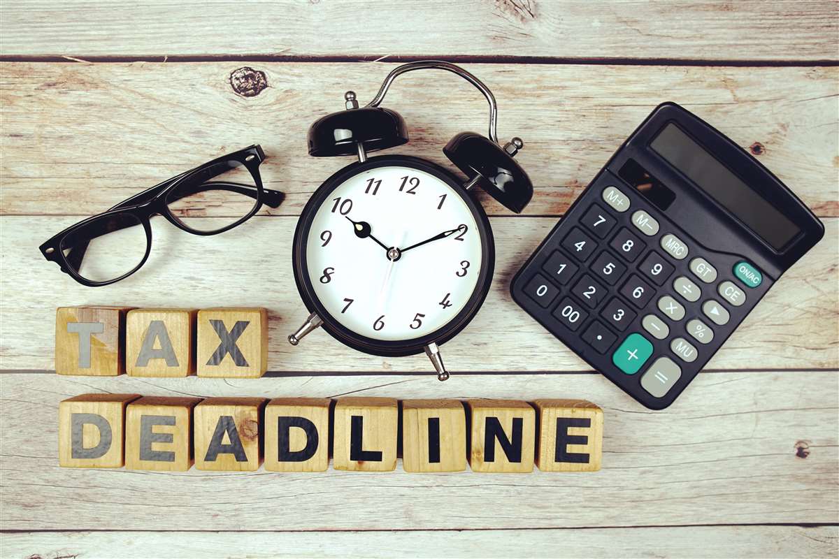scritta tax deadline, orologio, calcolatrice e occhiali