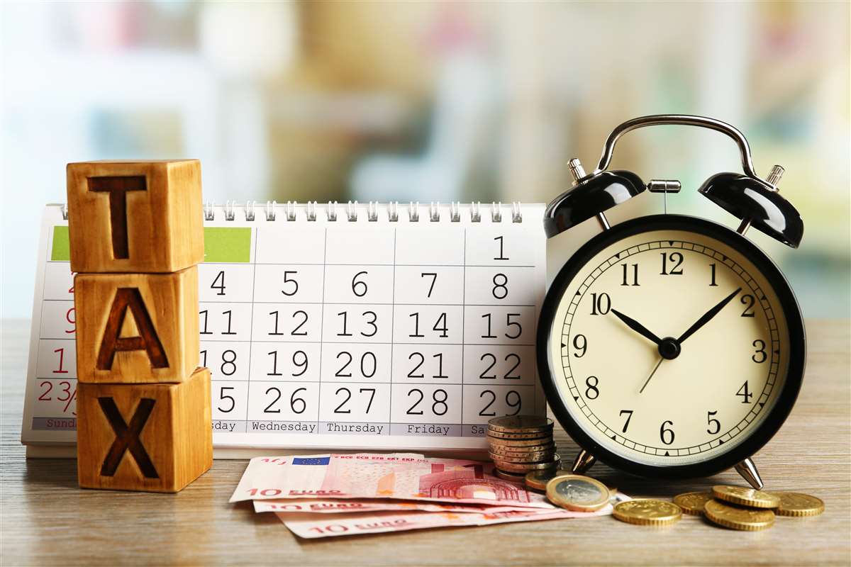 cubi in legno con incisa la scritta tax, calendario, orologio sveglia e soldi